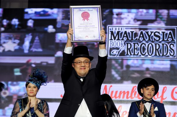 Dr. Lim Teck Ting holding up the Malaysia Book of Records for Most Number of Children In a Talent Competition